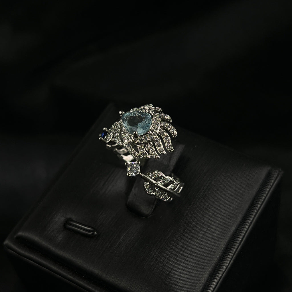 Eleganter Damenring im Feder-Design mit hellblauem Stein