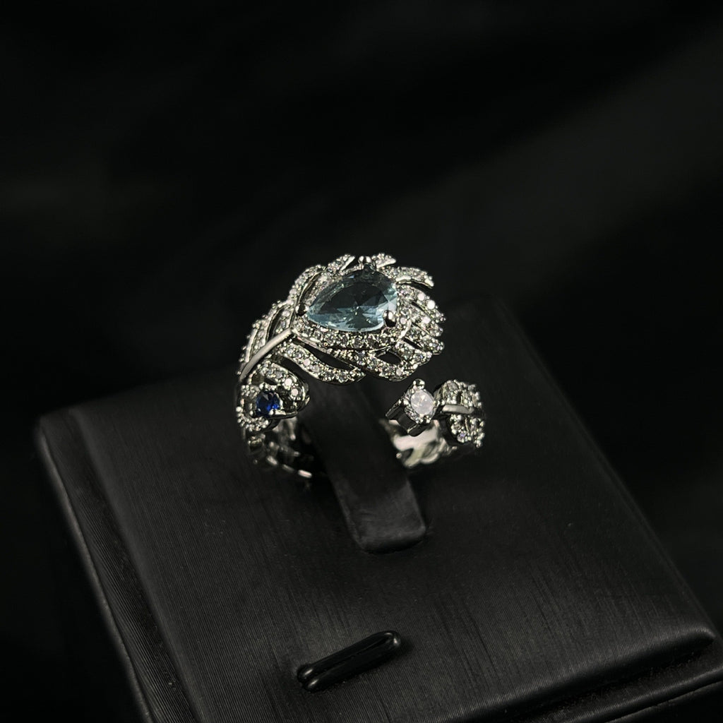 Eleganter Damenring im Feder-Design mit hellblauem Stein
